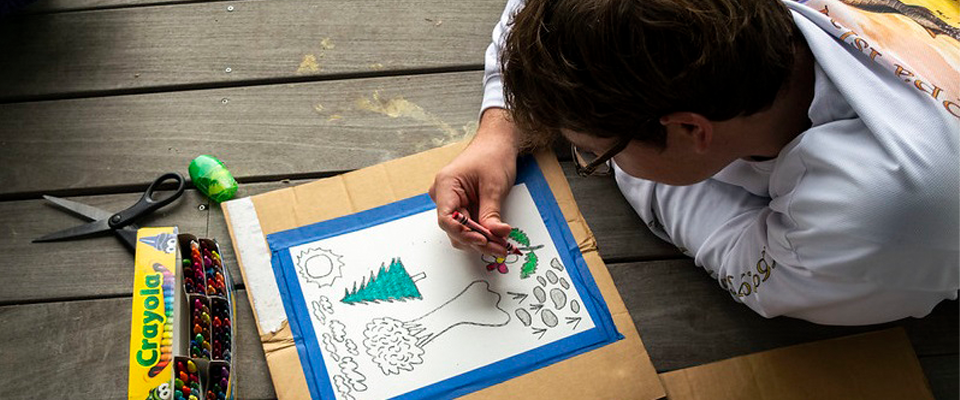 A student creates a drawing while reclining on a deck