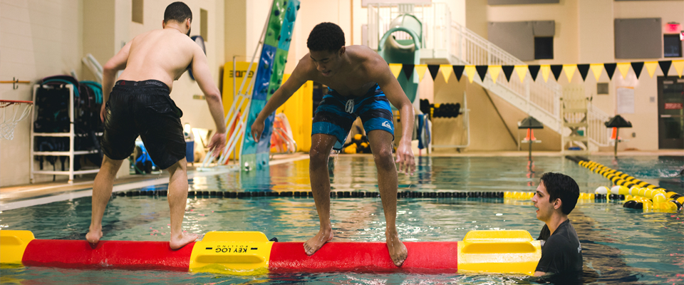 A student log rolls in the pool at the Cary Street Gym Aquatic Center