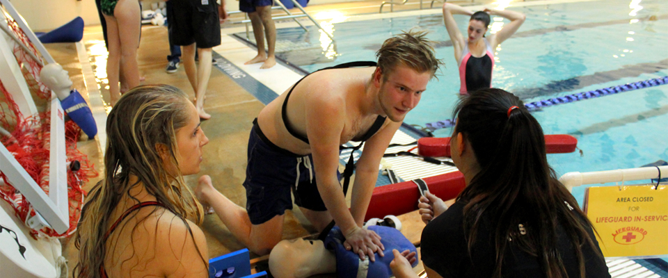 Lifeguards practice CPR with mannequins on the pool deck at Cary Street Gym Aquatic Center