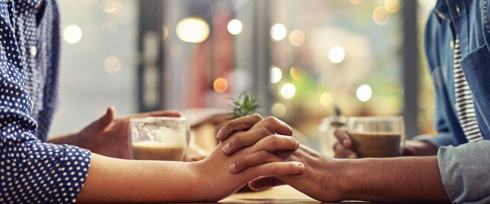 a couple holds hands at a table in a cafe